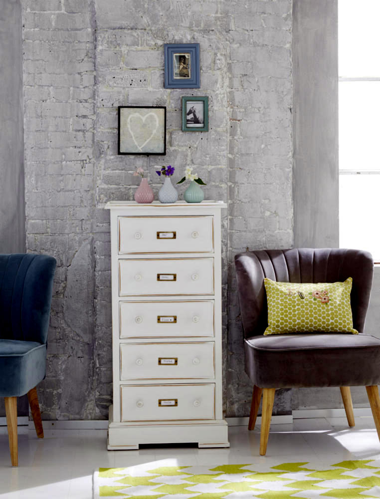 White chest of drawers in front of a gray brick wall ...